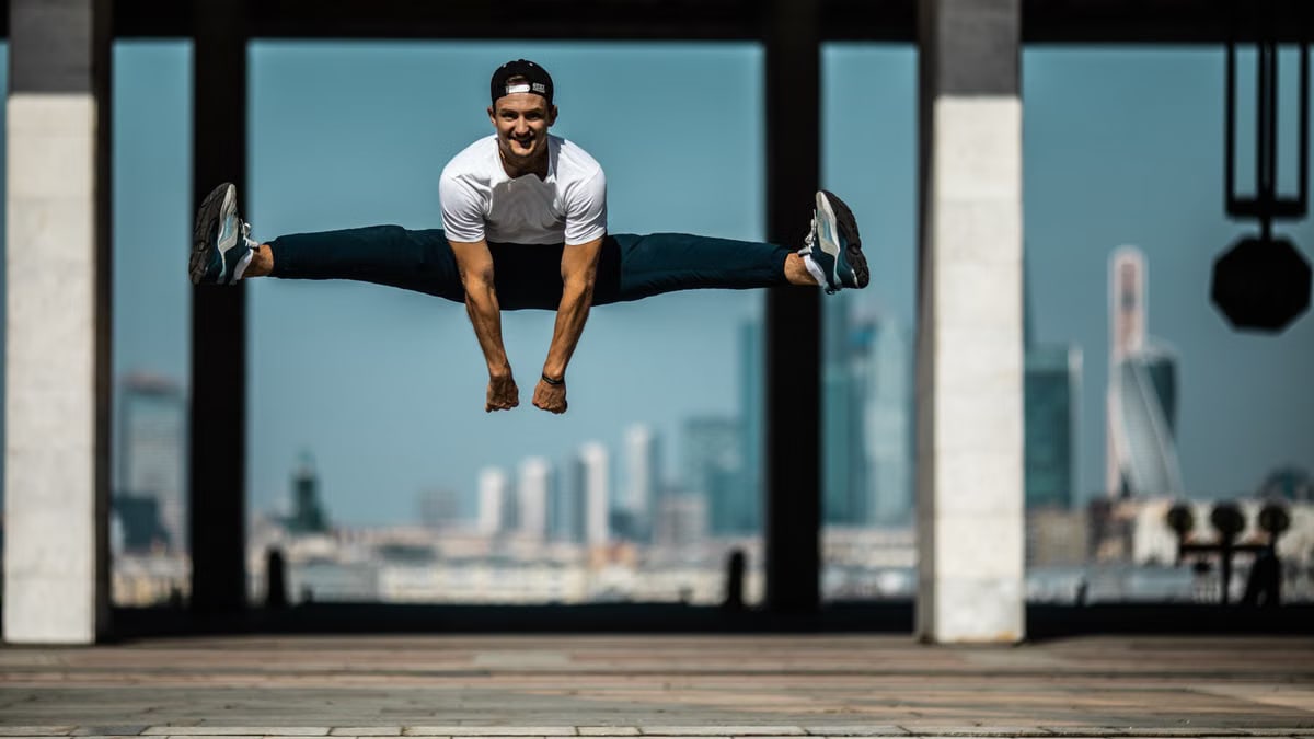 Man performing a split jump on concrete, showcasing fitness and agility.